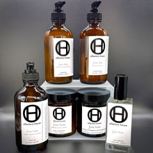 Faire Taire complete collection on a black background, including candle, eau fraîche, body moisturizer, body oil, shampoo, and conditioner.