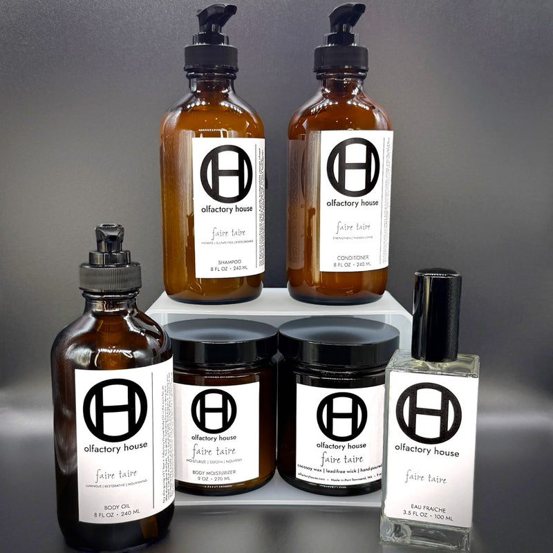 Faire Taire complete collection on a black background, including candle, eau fraîche, body moisturizer, body oil, shampoo, and conditioner.