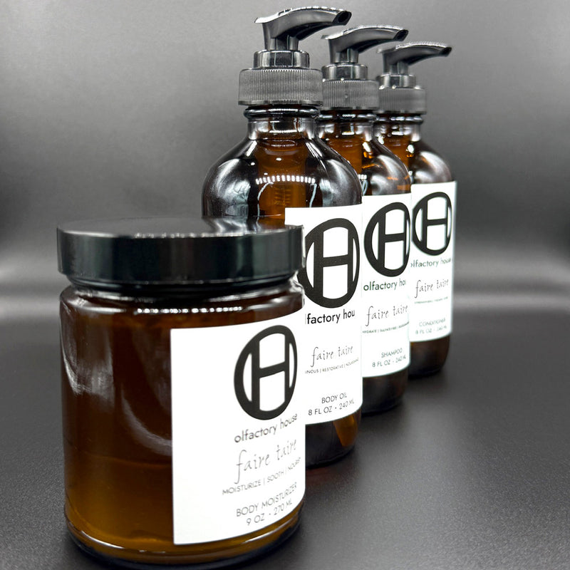Faire Taire body and hair care set on a black background, featuring body moisturizer, body oil, shampoo, and conditioner.
