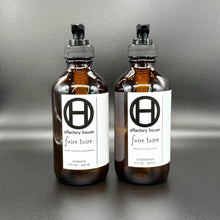 Faire Taire hair care duo on a black background, with shampoo and conditioner bottles side by side.